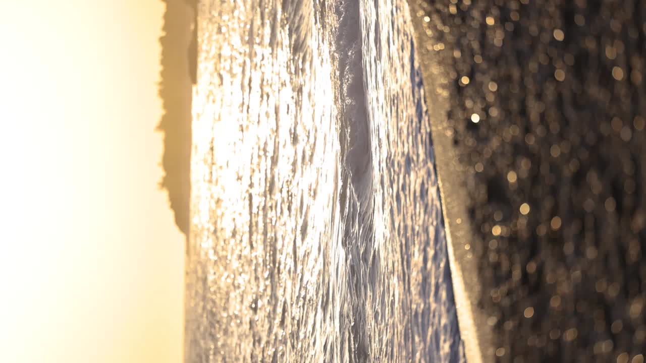 해가 지면 돌로 된 해변 에 부 ⁇ 히는 느린 움직임 의 파도 들 의 수직  ⁇