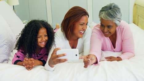 Family-reviewing-photos-on-mobile-phone-in-bedroom-4k