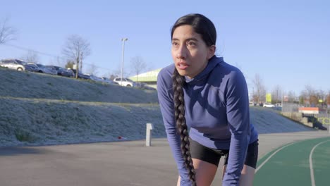 Strong-resilient-athletic-woman-running-in-Winter-stops-to-rest