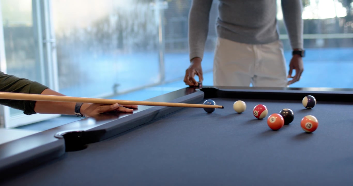 Des hommes afro-américains repérant un coup ouvert, s'alignant et frappant la boule blanche sur une table de billard au tapis bleu.