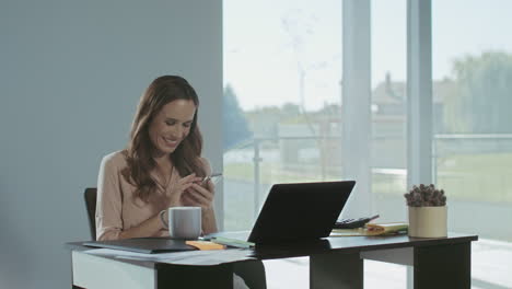 business woman scrolling mobile at work place. smiling lady having break.