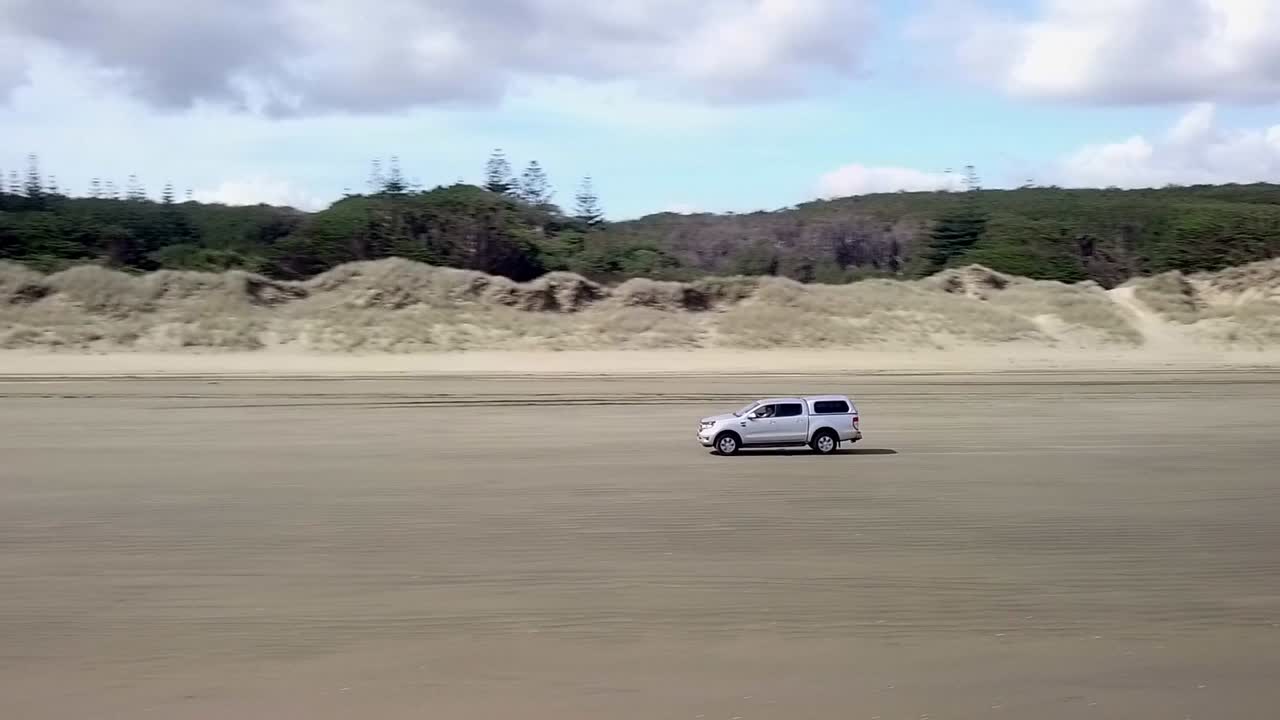 뉴질랜드의 90 마일 해변을 따라 운전하는 4wd 트럭의 드론 파노라마