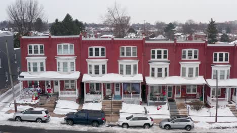 red rowhomes covered in snow, decorated for winter christmas holiday