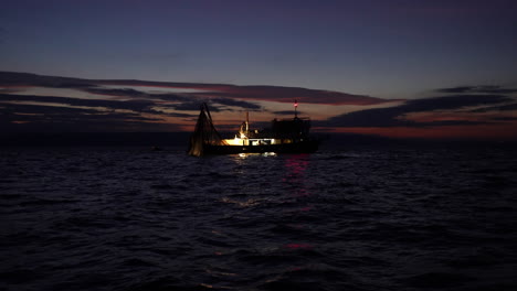 fisherman on a lighted boat fishing at the adriatic sea during daybreak