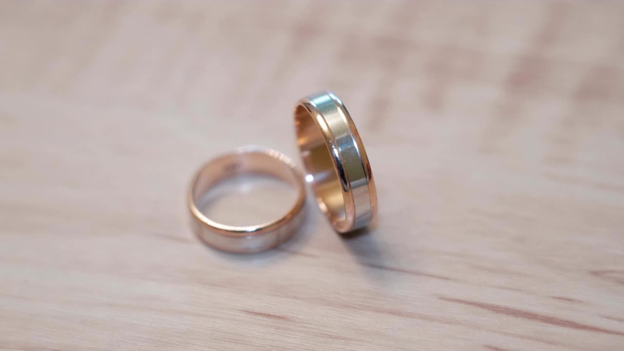 Wedding rings and play with the light on the wooden background close-up