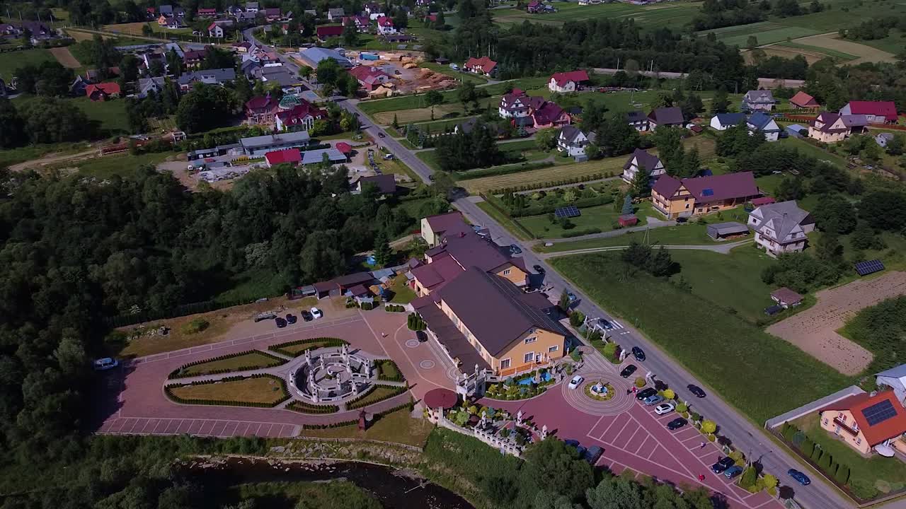 полет над пригородным районом с домами и огромной гостиницей с парковкой