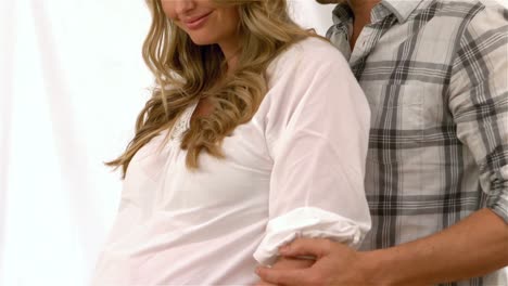 happy future parents standing against sofa