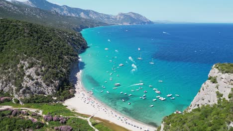 Barcos-Y-Turistas-En-La-Playa-De-Cala-Luna,-Costa-De-Baunei,-Cerdeña,-Italia---Antena-4k