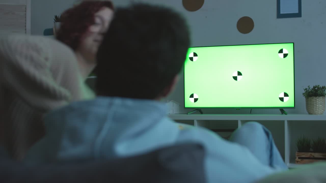 coppia che guarda la tv a schermo verde al crepuscolo