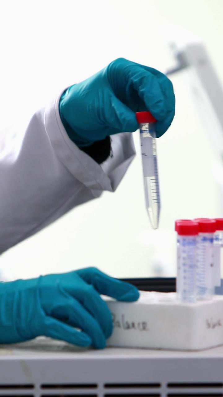 Ponto de luz azul contra a parte central de cientista caucasiana colocando tubos de ensaio em uma máquina