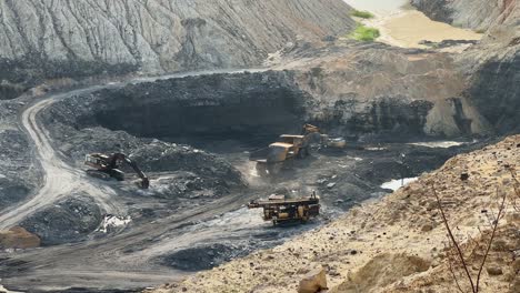 static shot showing an immense quarry dump truck, traverses the designated haul road within an open-pit coal mine for loading coal