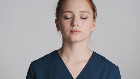 redheaded doctor in front of camera on gray background.