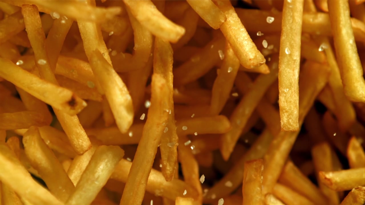 Súper cámara lenta de sal cayendo sobre papas fritas