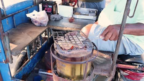 vendor grills squid on portable street barbecue.