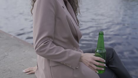 그녀의 친구와 이야기하고 강변에서 맥주를 마시는 행복한 곱슬 갈색 머리 여자