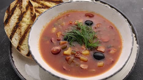 bowl of tomato soup with bread and olives