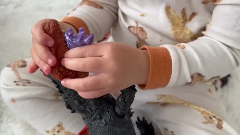 Small-toddler-hands-playing-with-a-Dinosaur-toy