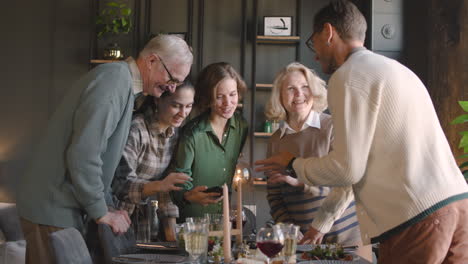 happy family looking something funny on mobile phone while having a meal together at home