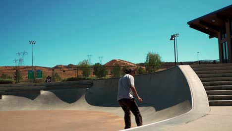 skilful skateboarder riding skateboard on edge of skate park, wide slow motion