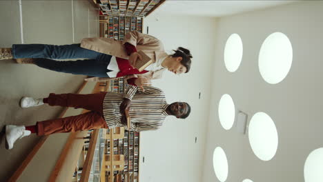 multiethnic man and woman walking in library and discussing books