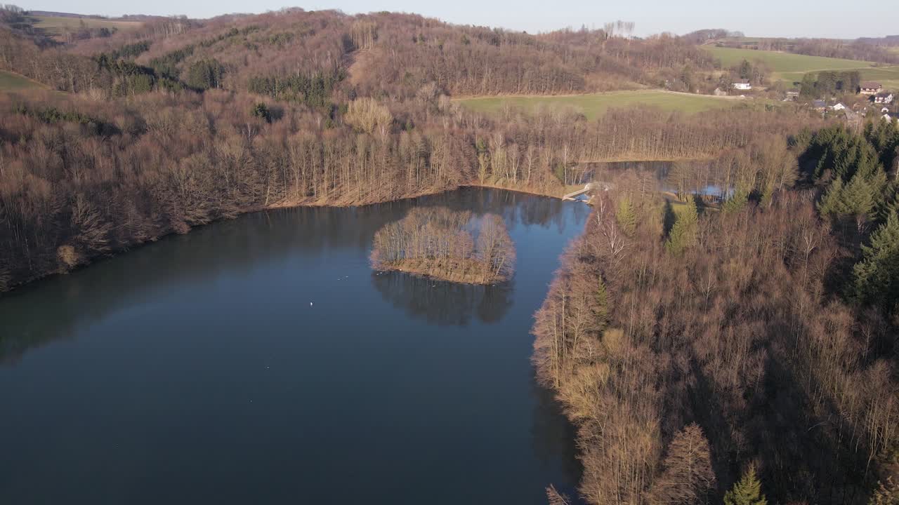 imágenes aéreas de un lago azul dentro de un paisaje de invierno marrón al atardecer