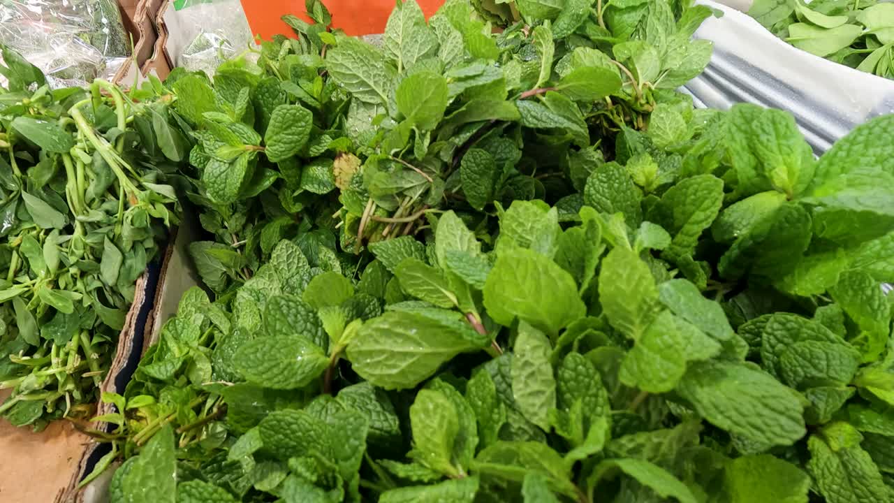 Vibrant green mint leaves arranged neatly on a market stall, captured with natural lighting and a steady camera angle