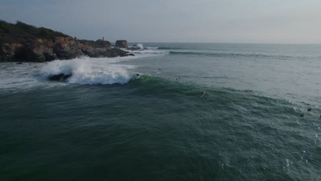 Vista-Aérea-Siguiendo-A-Los-Surfistas-Montando-Olas-Iluminadas-Por-El-Sol-En-Punta-Zicatela-Oaxaca-Paisaje-Marino-Del-Océano-Pacífico