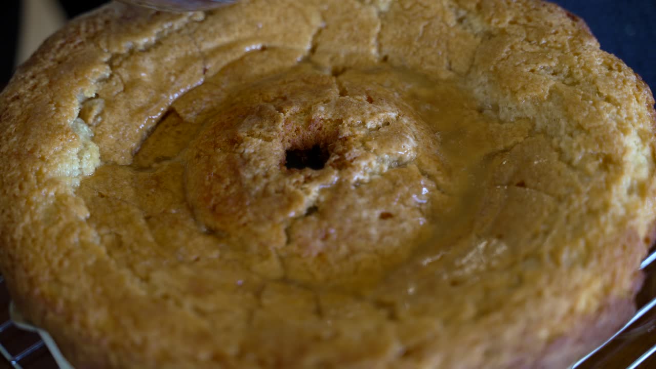 cuchareando el glaseado para que penetre en el fondo de un pastel de mantequilla de kentucky - serie de bizcochos