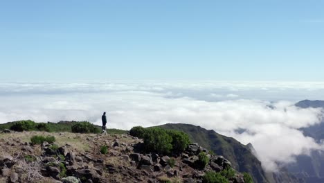 imágenes de drones de una mujer joven de pie en la cima de una montaña