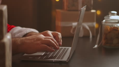 Papá-Noel-Responde-El-Correo-Electrónico-Del-Niño.-Escribiendo-En-El-Teclado-Del-Portátil.-La-Cámara-Recorre-A-Santa.-Fotografía-De-Cerca.-Imágenes-4k-De-Alta-Calidad