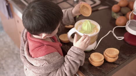 asian boy learning how to squeeze oranges to make juice by himself