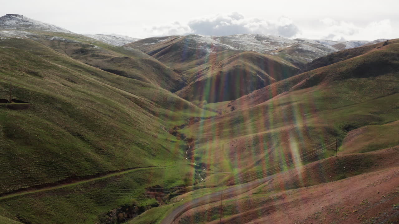 vista panorámica aérea de montañas verdes con bengalas solares brillando a través de las nubes