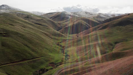 aerial panoramic view of green mountains with sun flare shining through clouds