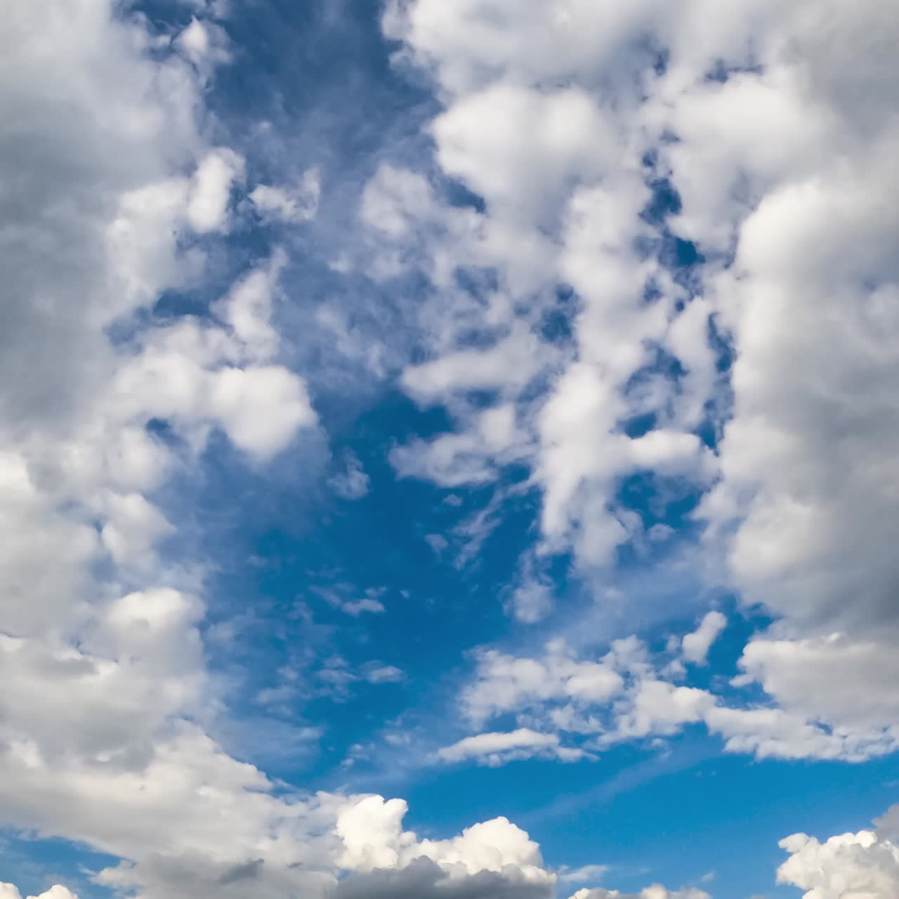Soft white clouds covering the blue sky. Low angle view timelapse on summer daytime