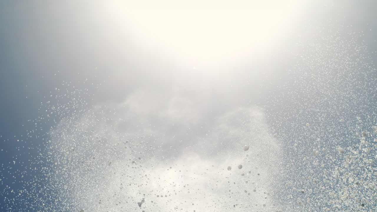 Ocean water mist shoots upward, captured in slow motion with dramatic sky overhead
