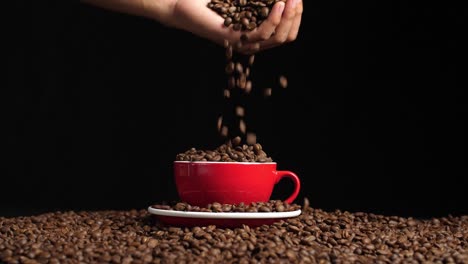 hand holding coffee beans pouring into red cup, slow motion