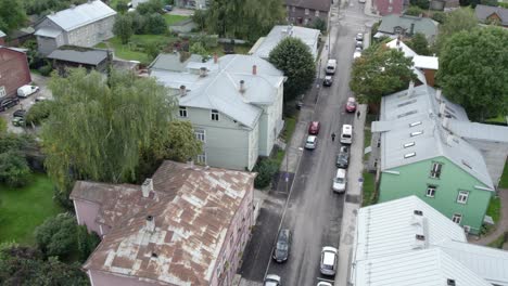 drone-recording-from-air-how-man-on-scooter-driving-middle-of-road-in-karlova-between-old-wooden-houses-on-Eha-street