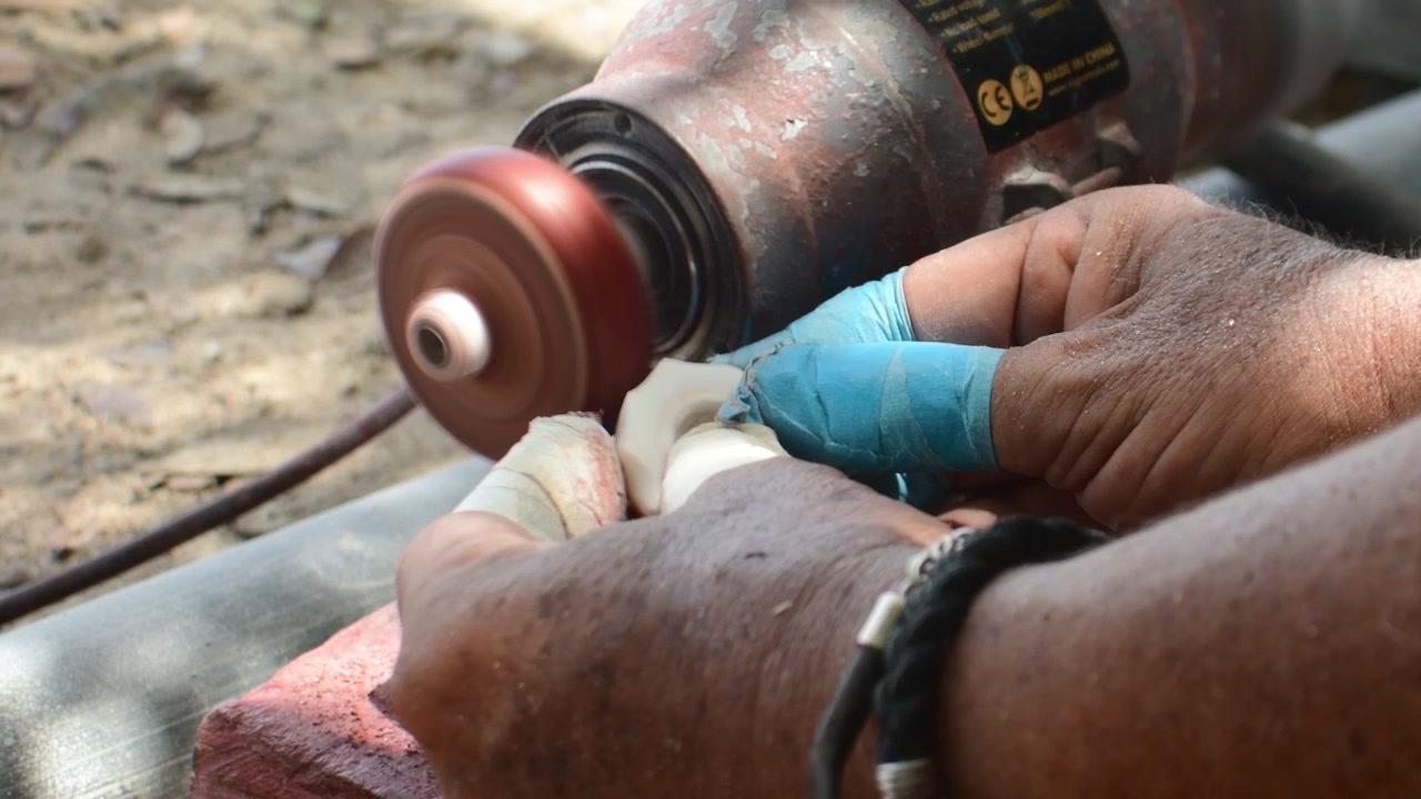 Authentic craftsmanship workshop.Traditional handmade production, precision finishing, and artisan techniques polishing a handcrafted seashell using rotating bench grinder. 4K D-Log ungraded footage.