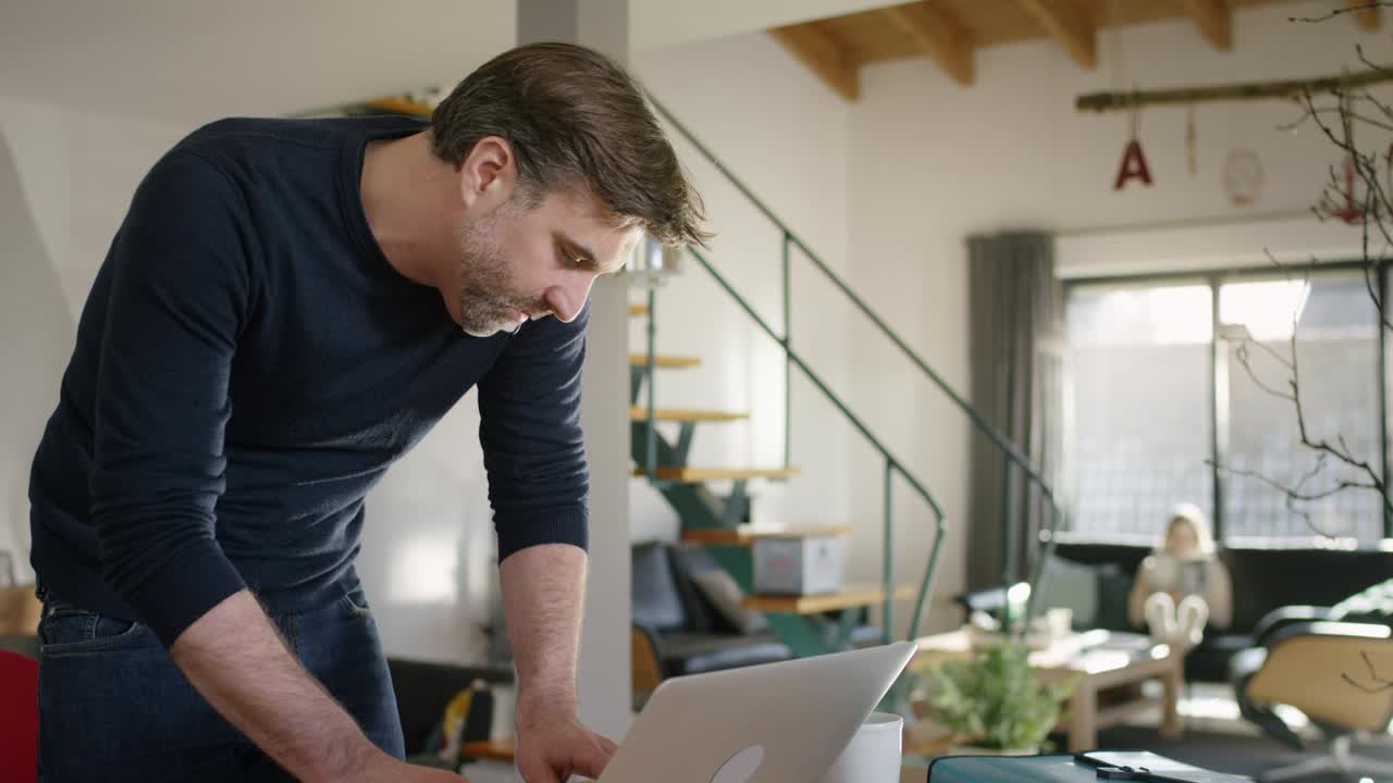 hombre guapo escribiendo en la computadora portátil mientras habla en la mano