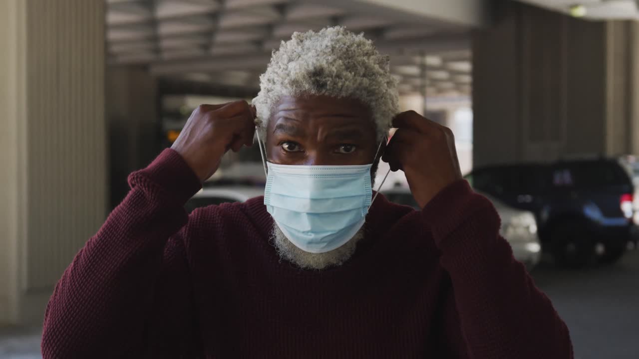 Portrett av afroamerikansk senior mann med ansiktsmaske på parkeringsplassen