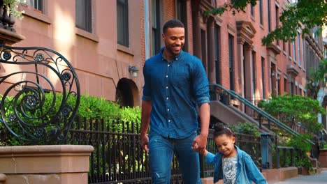 Father-and-daughter-walking-hand-in-hand-down-the-street