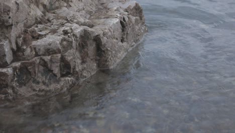 clear seawater with soft waves moving towards a rocky shore - medium shot