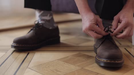 Close-up-hands-of-man-groom-adjusting,-wearing,-putting-his-wedding-shoes-in-hotel-room-near-window