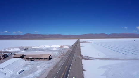 Aerial-pan-of-road-and-buildings-by-vast-salt-flats-in-Argentina