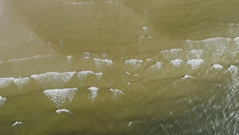 tropical beach aerial view, top view of waves break on tropical white sand beach. sea waves seamless loop on the beautiful sand beach.