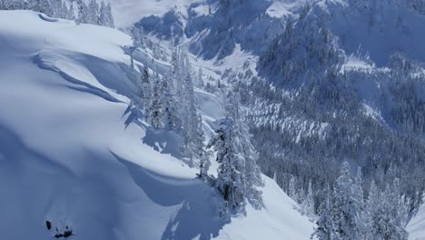 A-rotating-aerial-shot-of-cliffside-revealing-a-snow-covered-valley