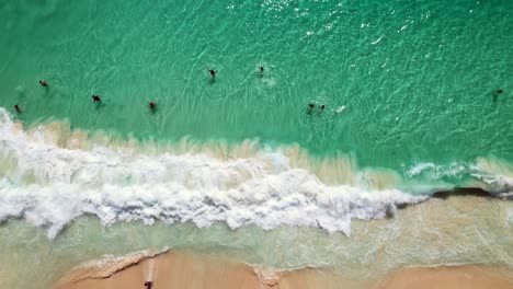 Mahe-Seychelles,-Drone-shot-of-clients-swimming-and-big-waves-crashing-on-the-shore