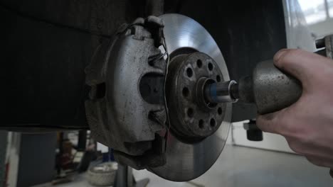 mecánico de automóviles reemplazando las patas de freno de la rueda del automóvil levantado en la estación de servicio de reparación