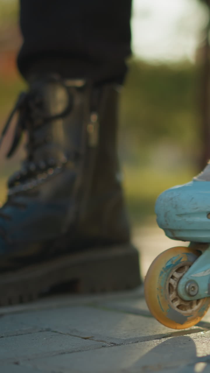A close-up shot of a person wearing a light blue rollerblade on one foot, with the rollerblade wheels in motion on the ground, while the other foot remains in a black boot