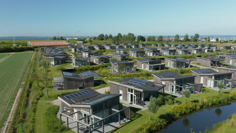 aerial view of stylish house at water village with solar panels installed on roof in kamperland, zeeland, netherlands